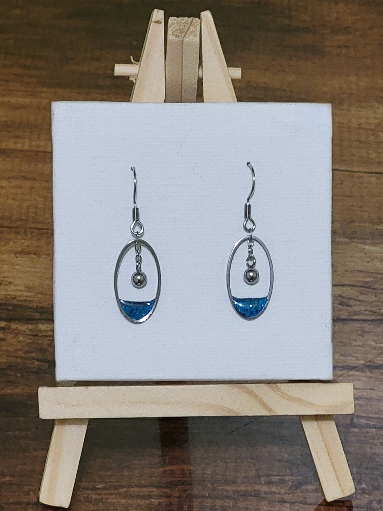 Boucles d’oreilles bleues en acier inoxydable argenté avec résine pailletée et pendentif boule – création artisanale Perle et Coquette